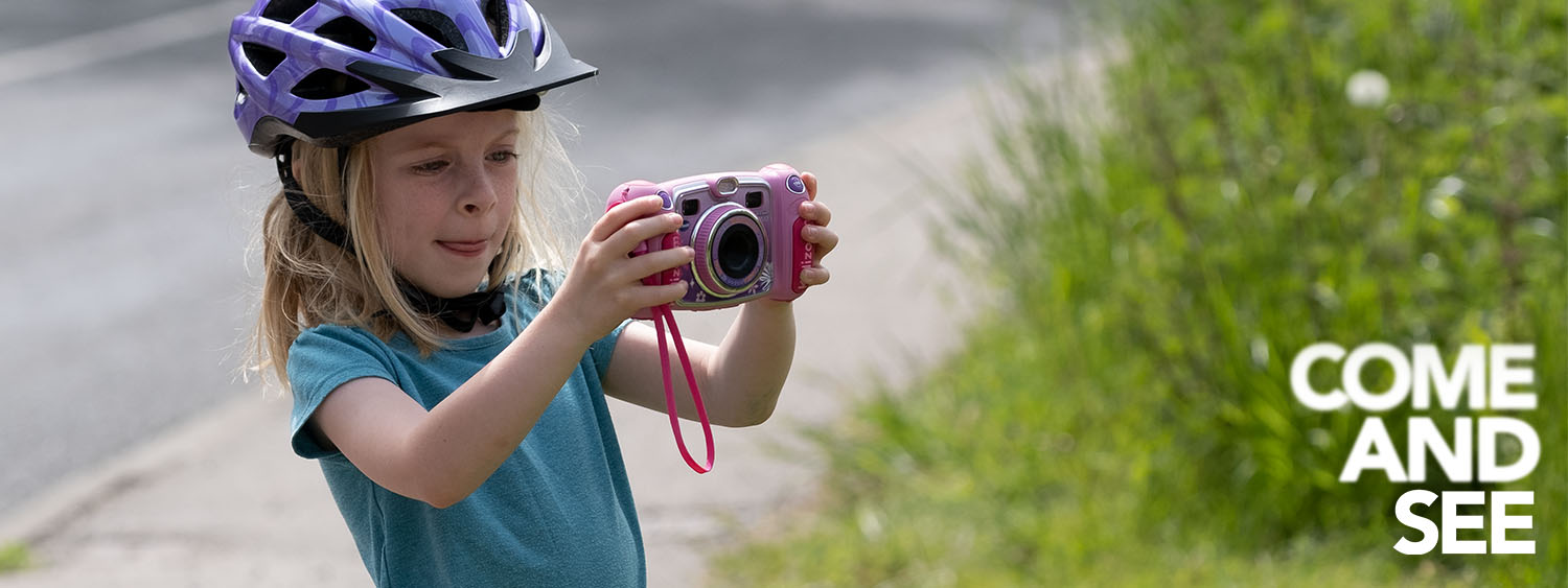 A girl wearing a bike helmet stops to take a photo
