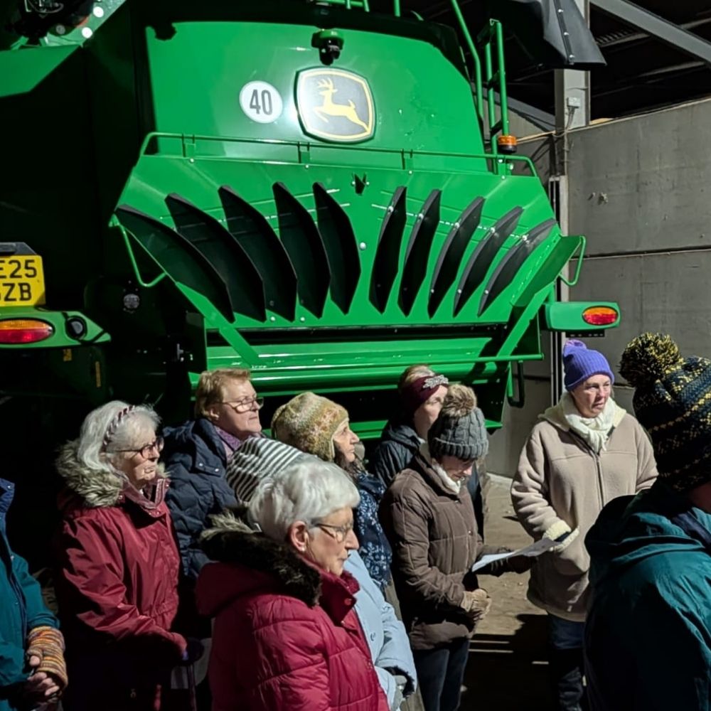 The Wild Church choir sings at Plough Sunday service in front of a combine harvester. 
