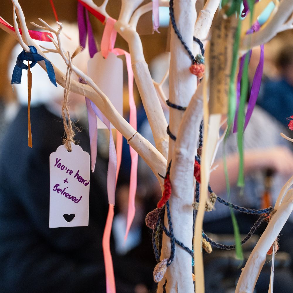 Tree of handwritten prayers, with one in focus reading 'you are heard and believed'