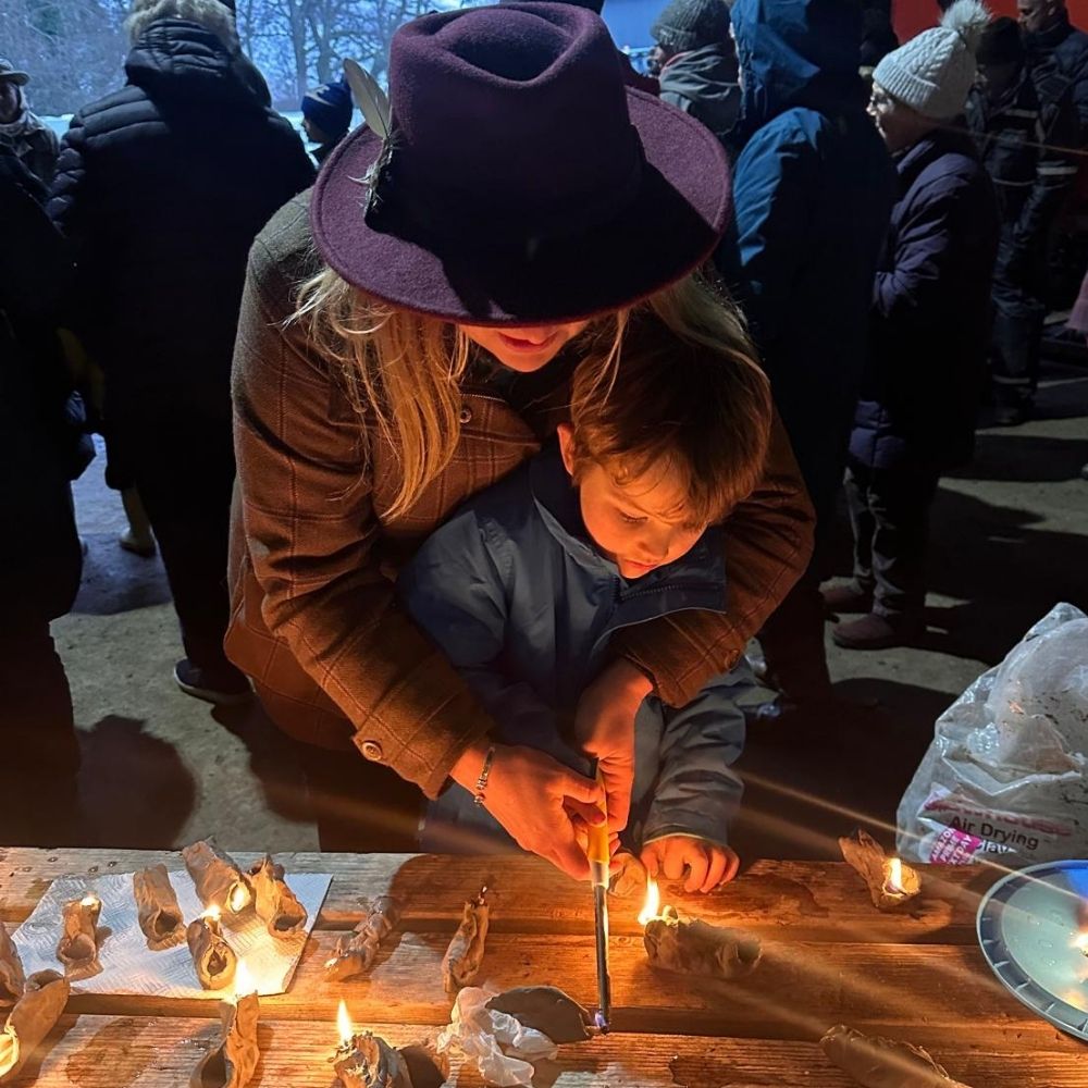 Farmer Bella lights a homemade clay plough light with her son. 