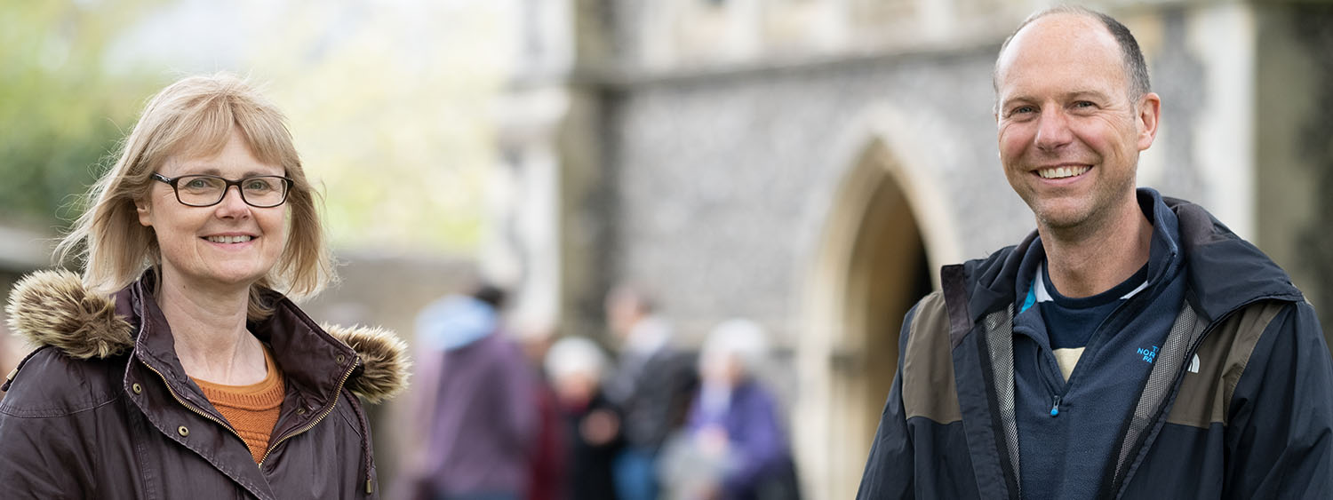 Woman and a man outside a parish church. Congregation in background.