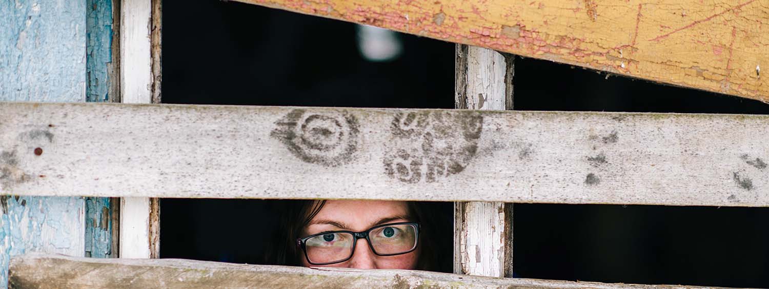 Illustrative photograph of modern slavery. A woman looks between wooden bards,