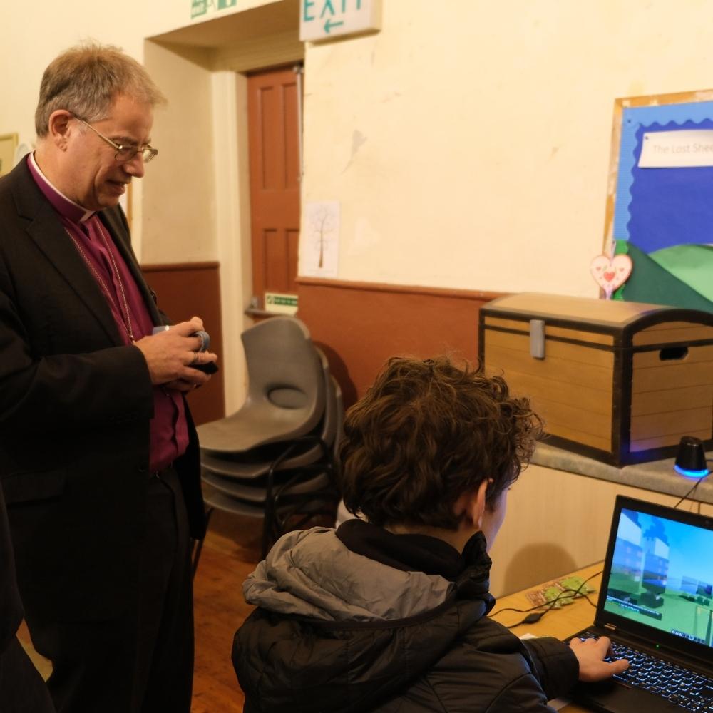 The Bishop of Oxford standing watching youth group members playing minecraft