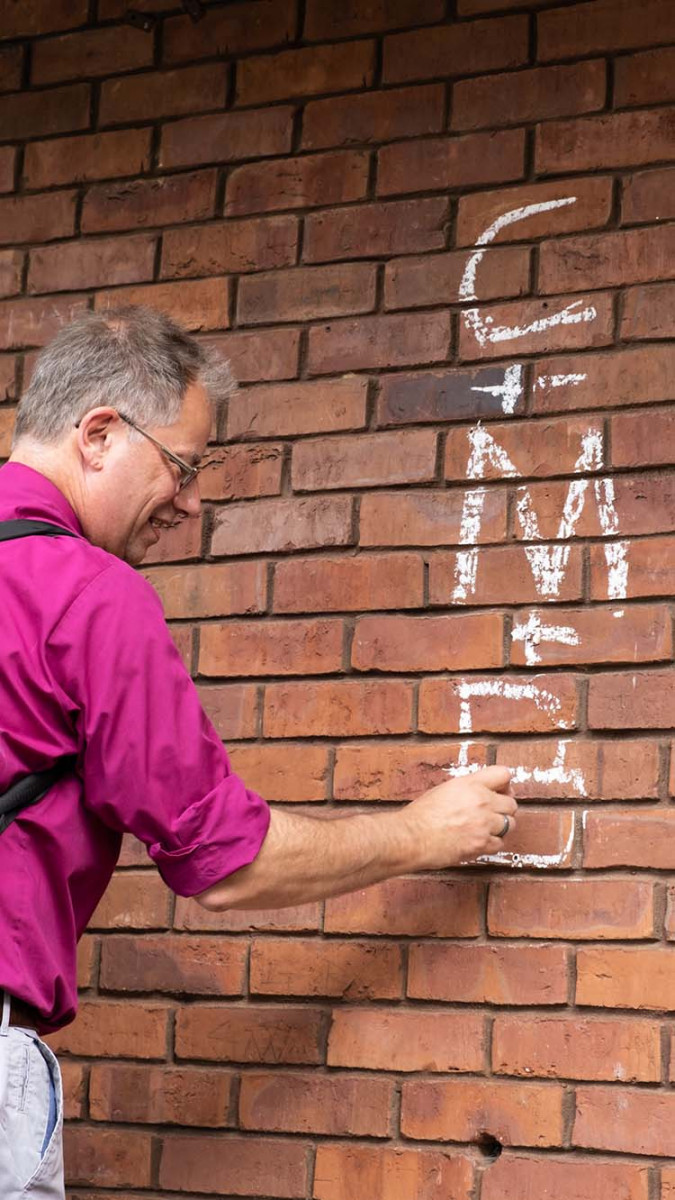 Bishop Steven chalks the wall of a church