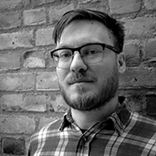 Black and white headshot of the Revd Ross Meikle, standing in front of a brick wall