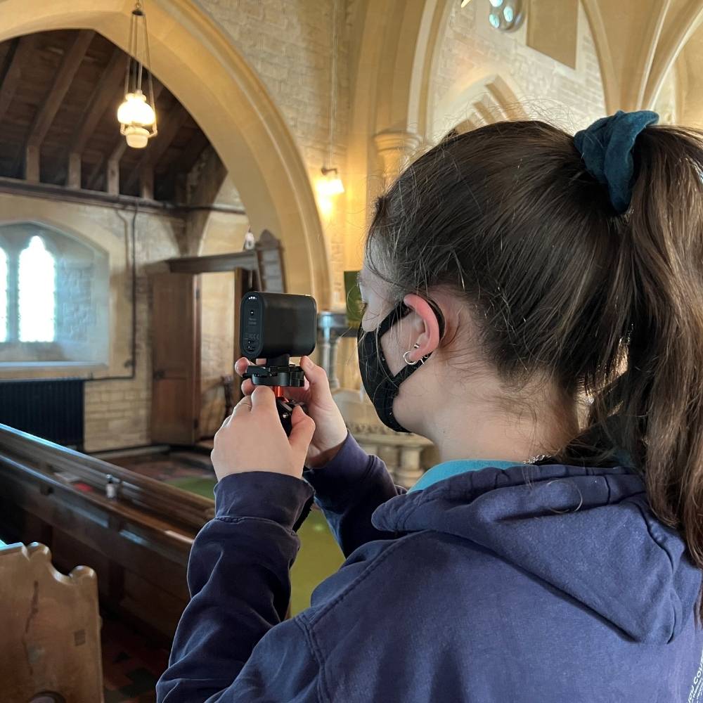 Teenage girl setting up camera on a tripod in a church
