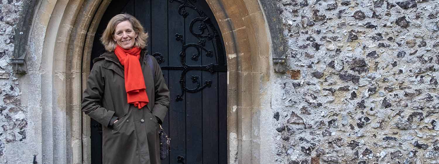 Julia Ogilvy stands in front of a large wooden church door