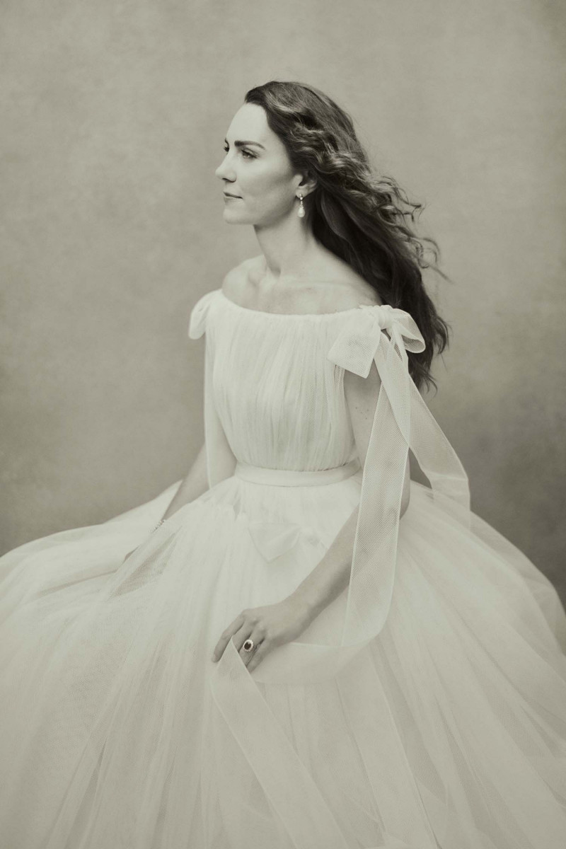 Photo portrait of HRH The Duchess of Cambridge by Paolo Roversi, to mark the Duchess's 40th birthday. It is a greyscale photo of The Duchess seated, gazing to the left, wearing a flowing white off the shoulder dress.