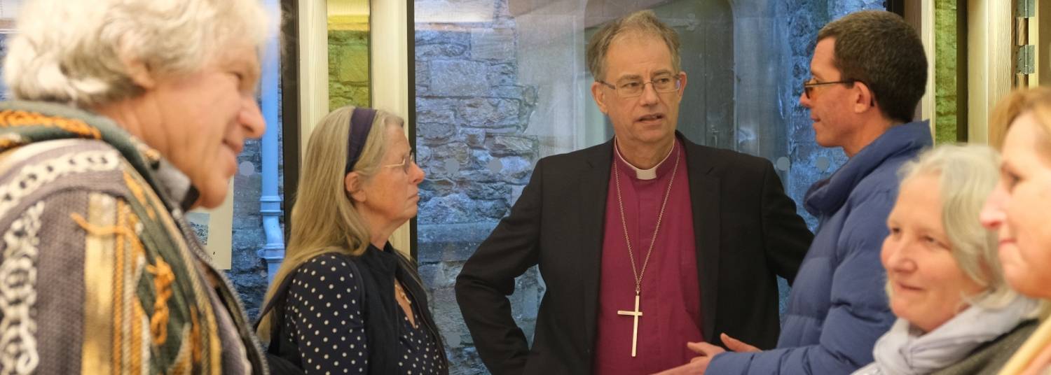 Bishop Steven standing talking to churchwardens at All Saint's Farringdon in the background and 3 churchwardens talking and smiling in the foreground.