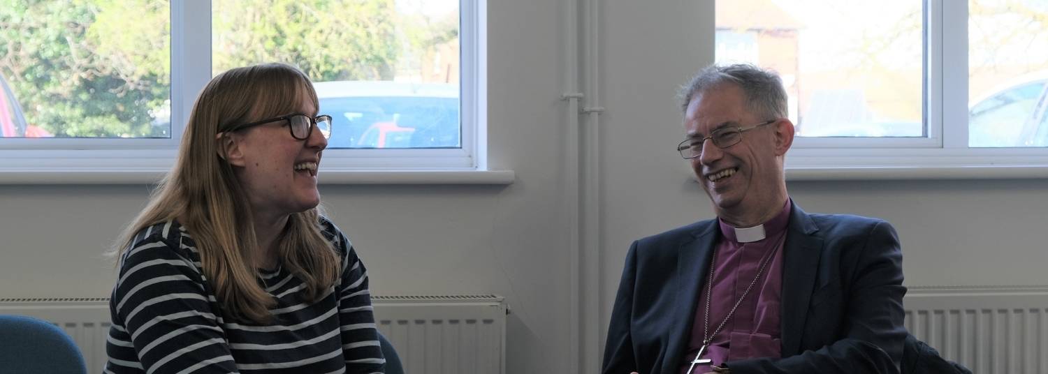 Bishop Steven sitting smiling with Hannah Field, Youth Worker in Didcot, Hannah is wearing a blue and white stripe top and glasses.