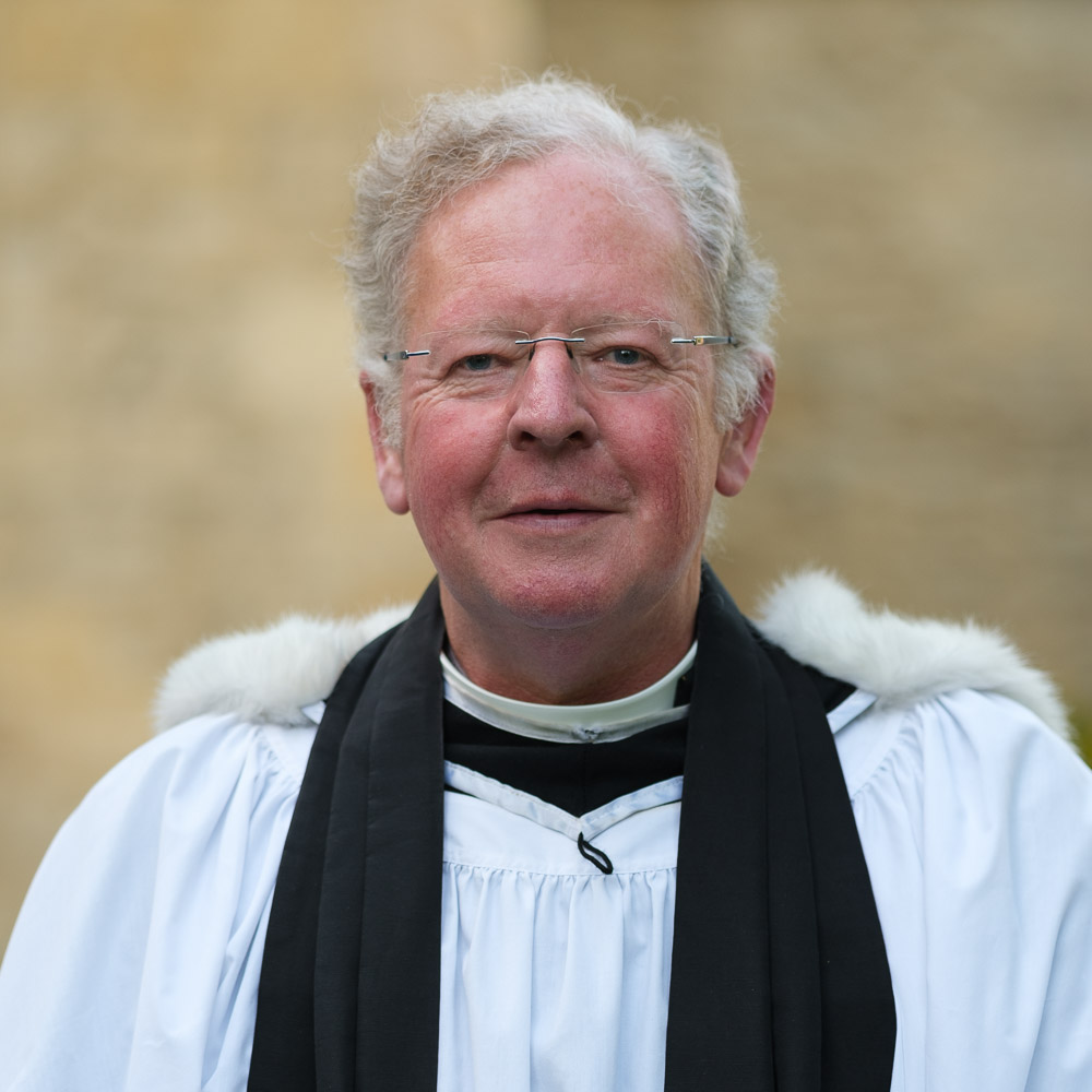 John Cook smiling wearing clerical robes.