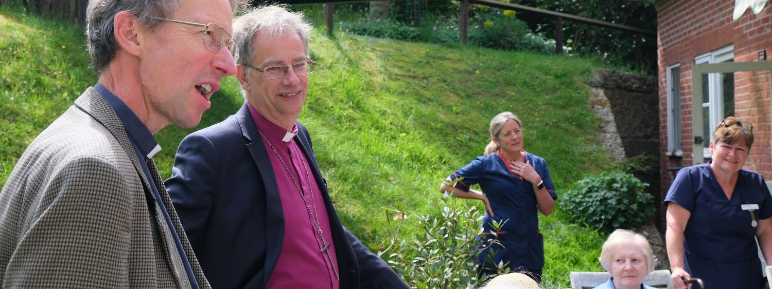 Bishop Steven standing in garden with staff and residents of Coombe House