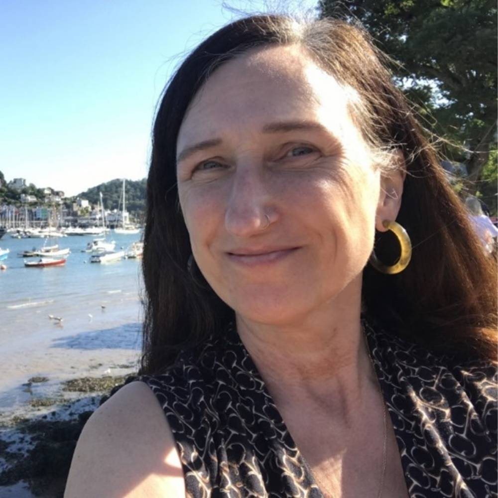 Selfie of Sue Hughes with harbour and sailing boats in the background