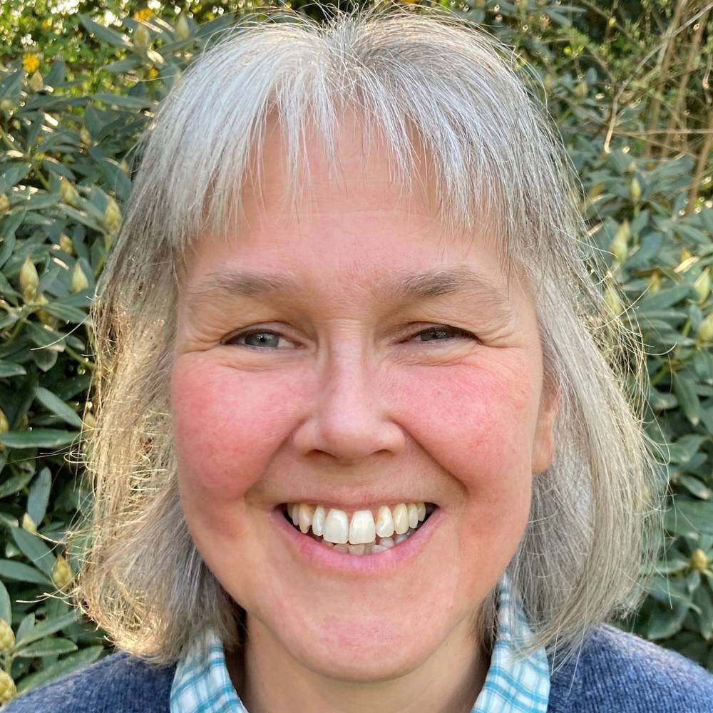 Headshot of Kimonie smiling and stood infront of a hedge