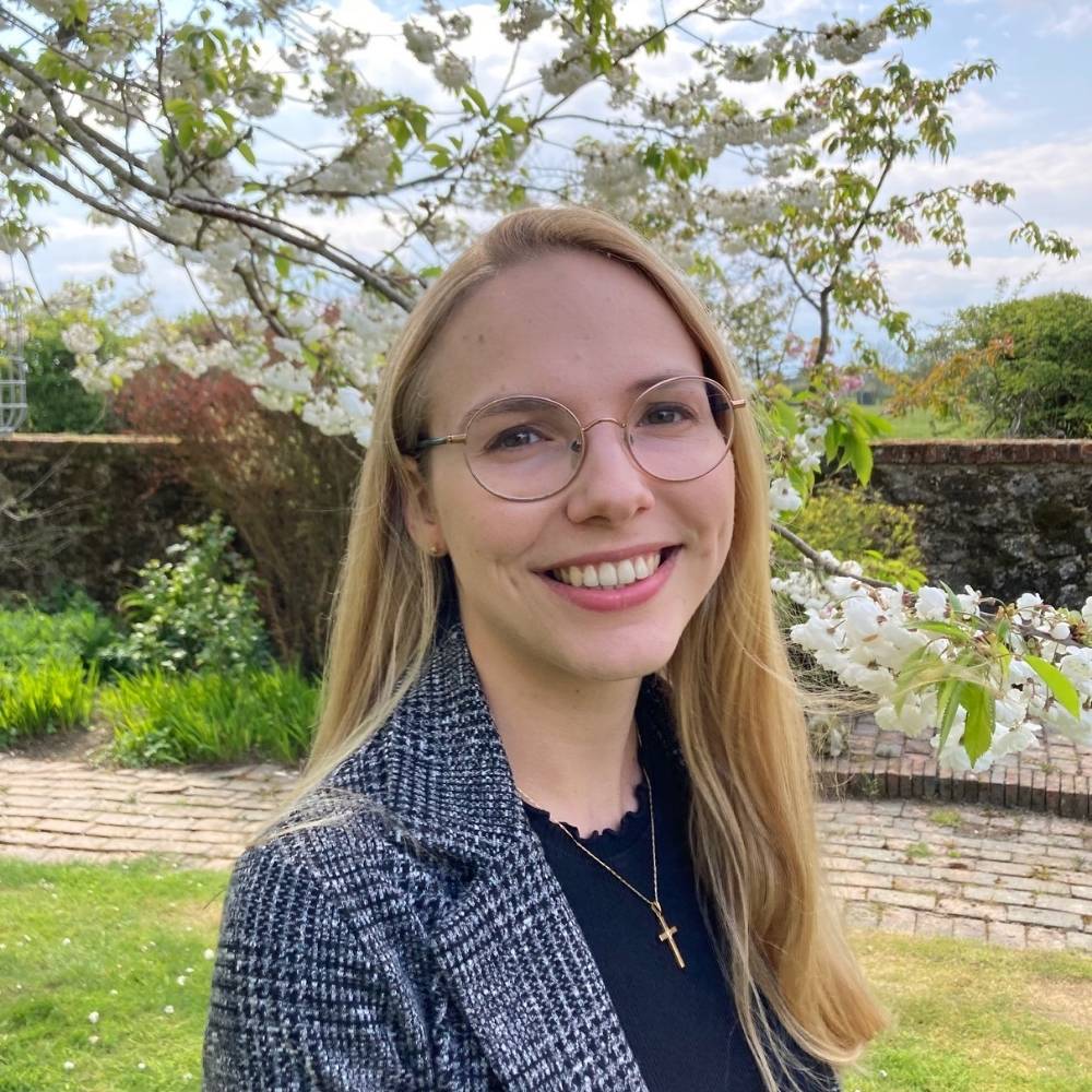 Francesca is standing smiling underneath a blossom tree