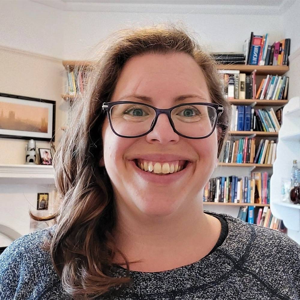 Headshot of Jen smiling and bookshelves in the background