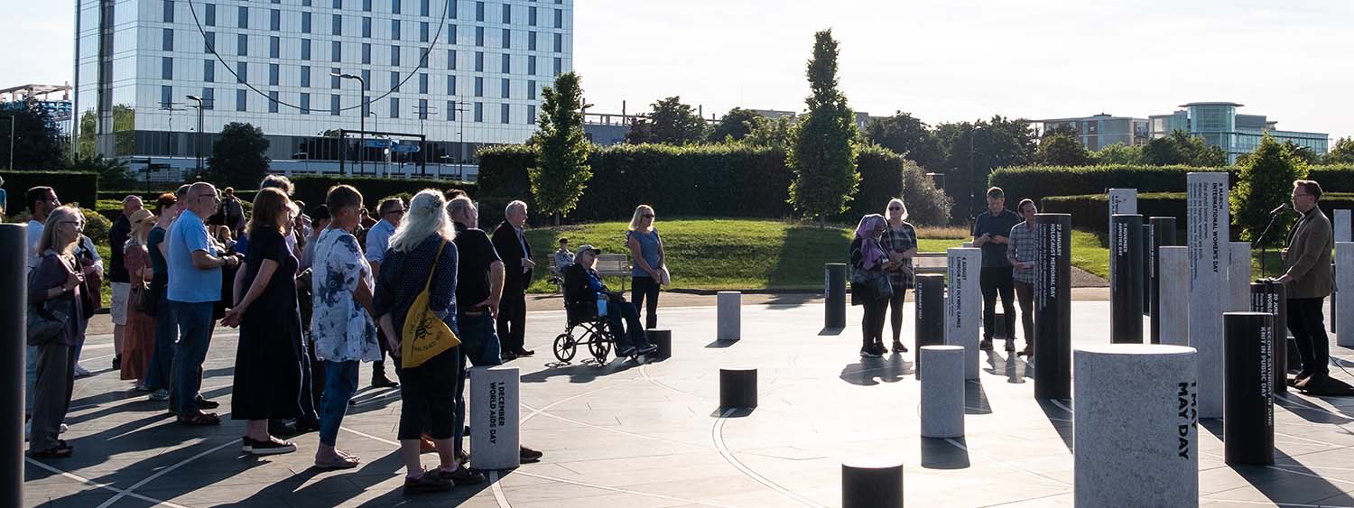 A crowd gather to hear a speaker at the Milton Keynes Rose, an open air art installation consisting of a collection of commemorative pillars each inscribed with an important date or issue
