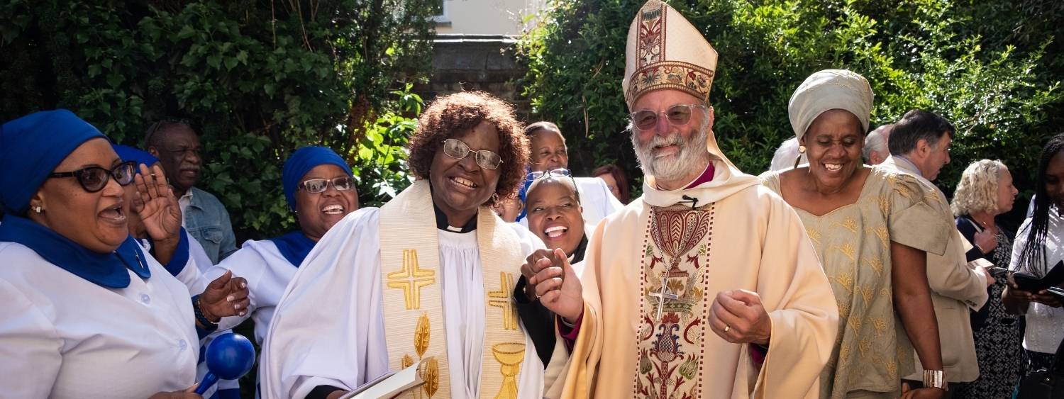 Bishop Alan and the Revd Rainah Madzorera with friends standing dancing and singing