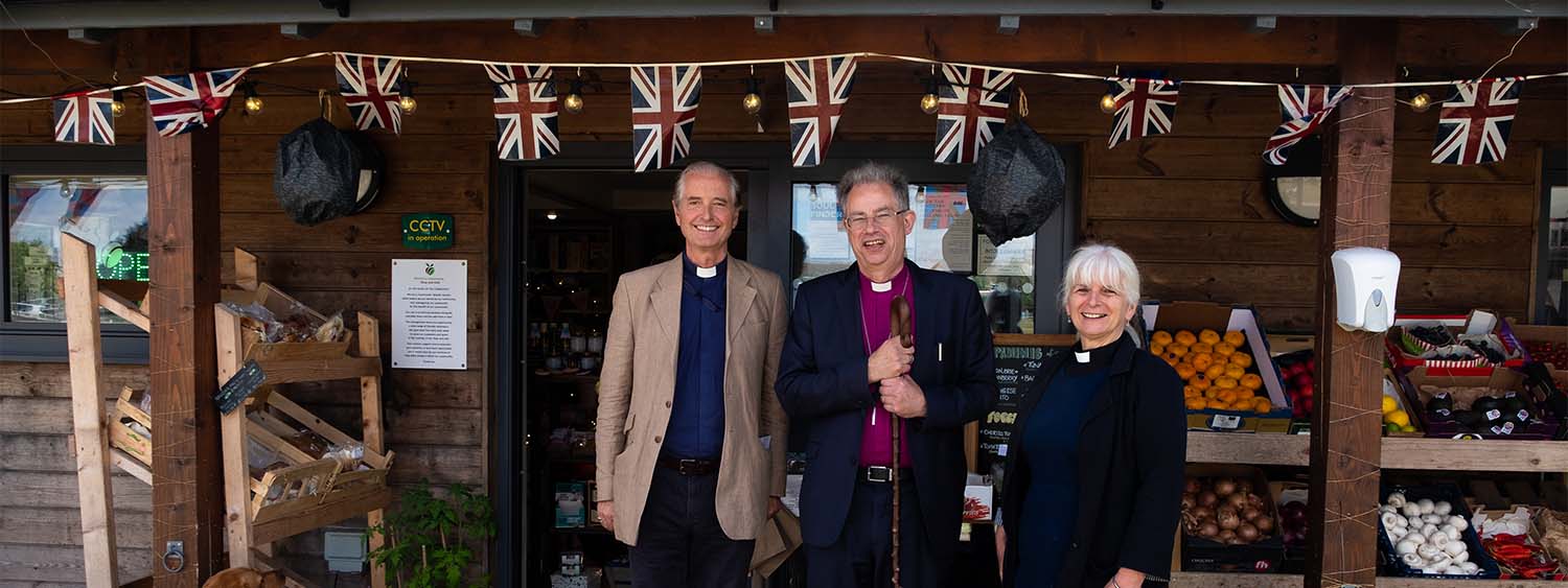 Bishop Steven and the Revs Will Pearson-Gee and Paula Smith stand outside the fruit and veg stall at Westbury Community Shop & Cafe