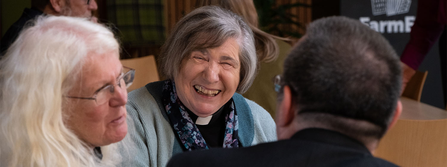 A member of clergy laughs as she speaks to the Bishop of Dorchester and another clergywoman.