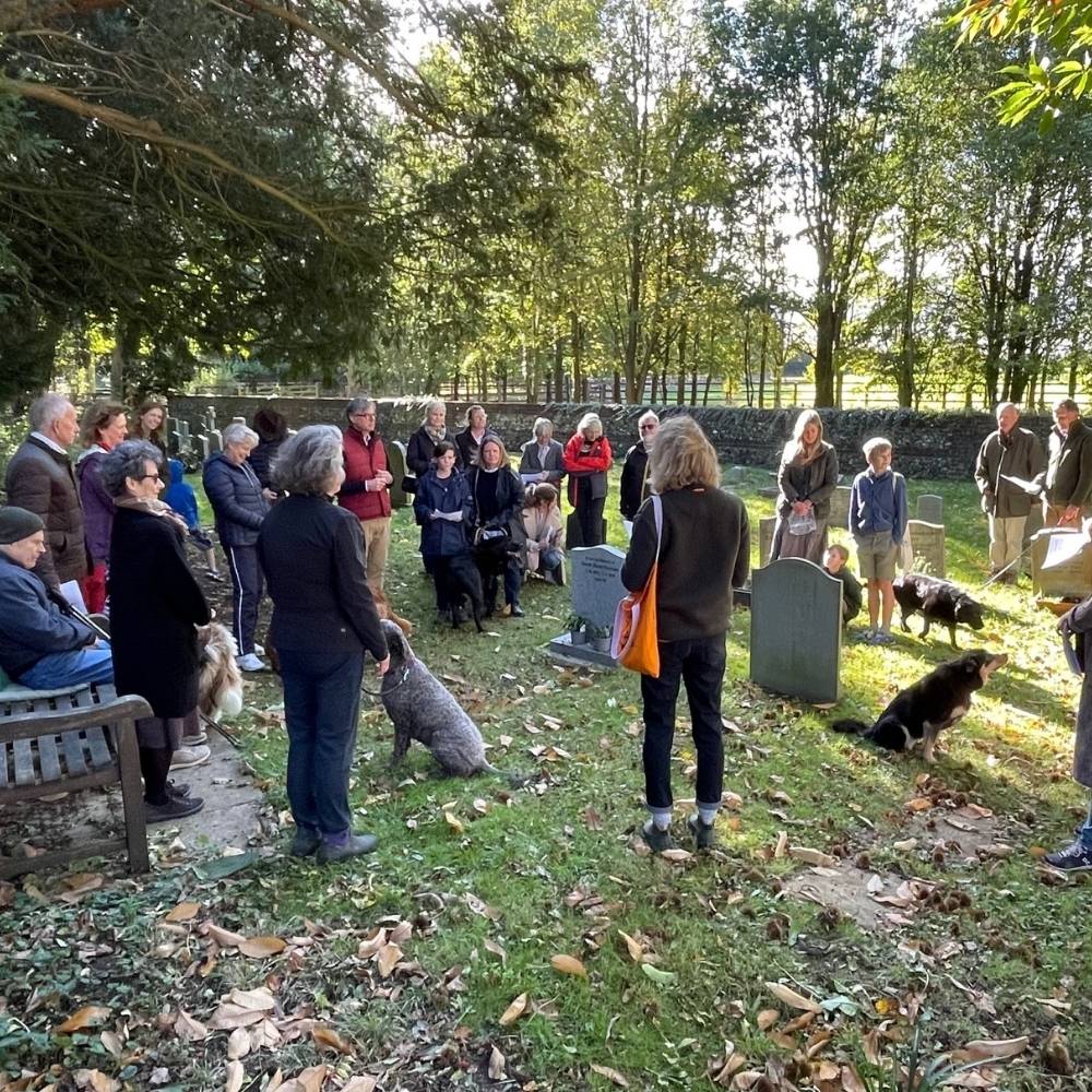 Group of people stood outside among grave yard praying together