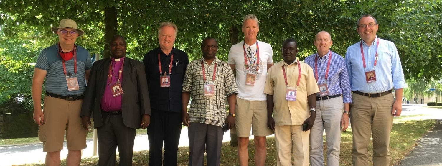 Bishop Gavin Collins and other Bishops from the Anglican Communion standing smiling in the shade of trees