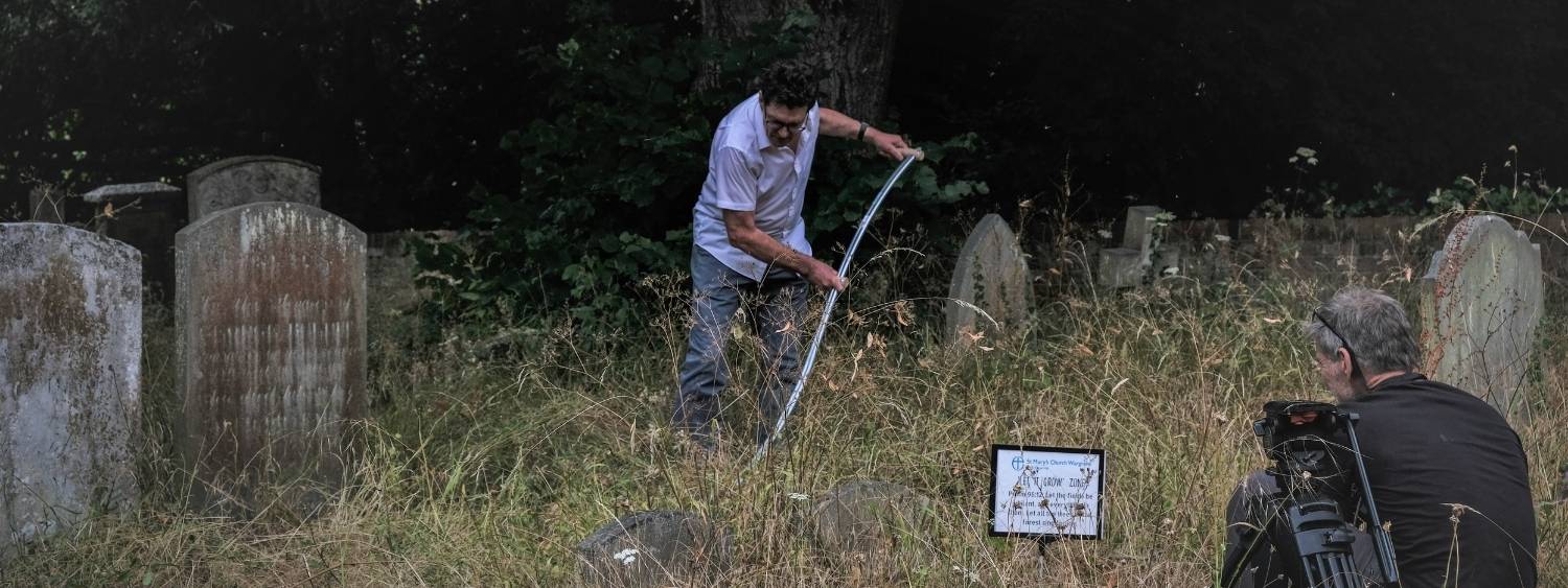Mike Buckland using a scythe to cut the rewilded areas of the St Mary's Churchyard in Wargrave