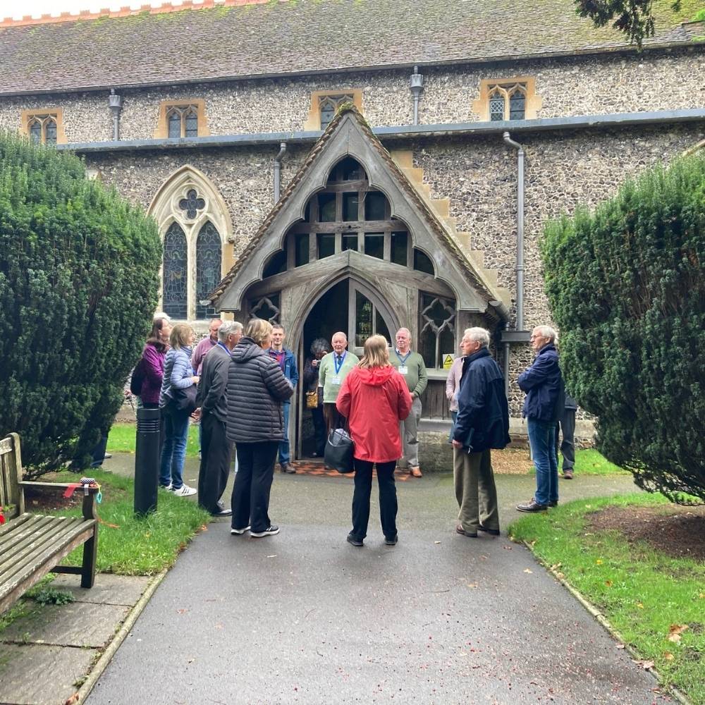 A group of people stand outside a church building in a circle talking