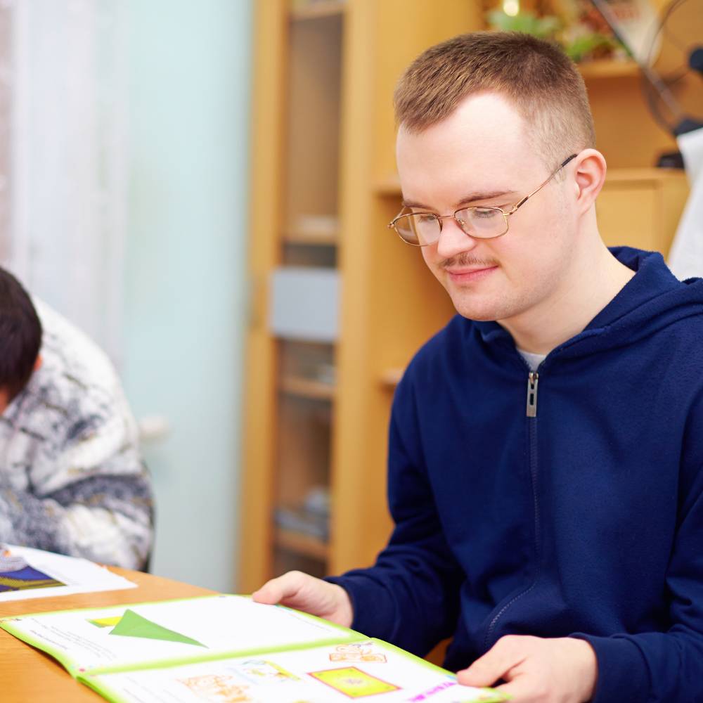 young adult male with additional needs sitting at a table doing crafts