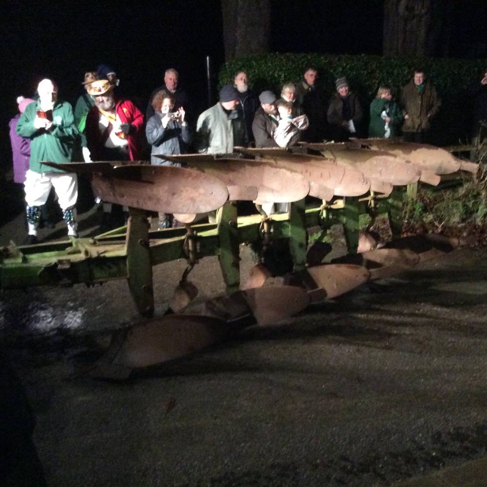 Large plough sitting in a road with people standing around it