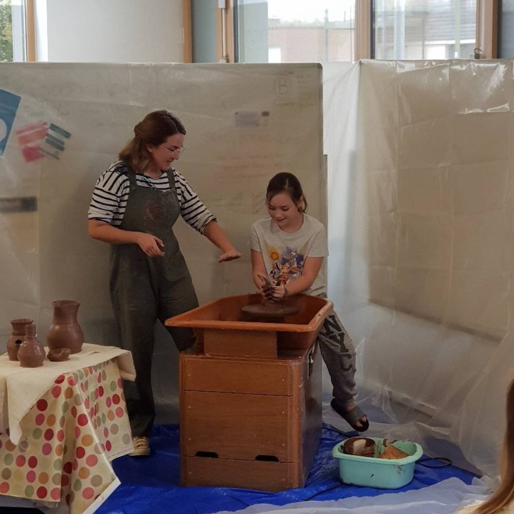 Young girl and young woman pottery making using a wheel.