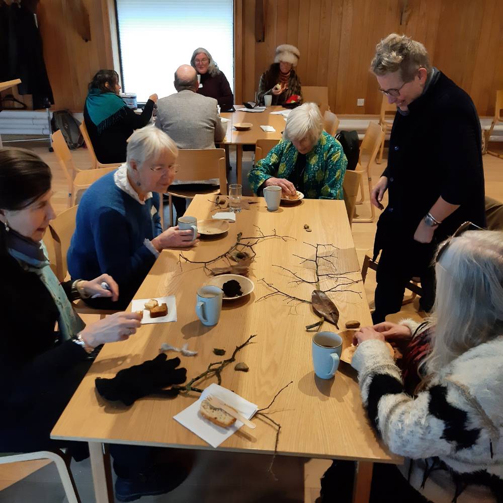 Group sit round a table with leaves and twigs