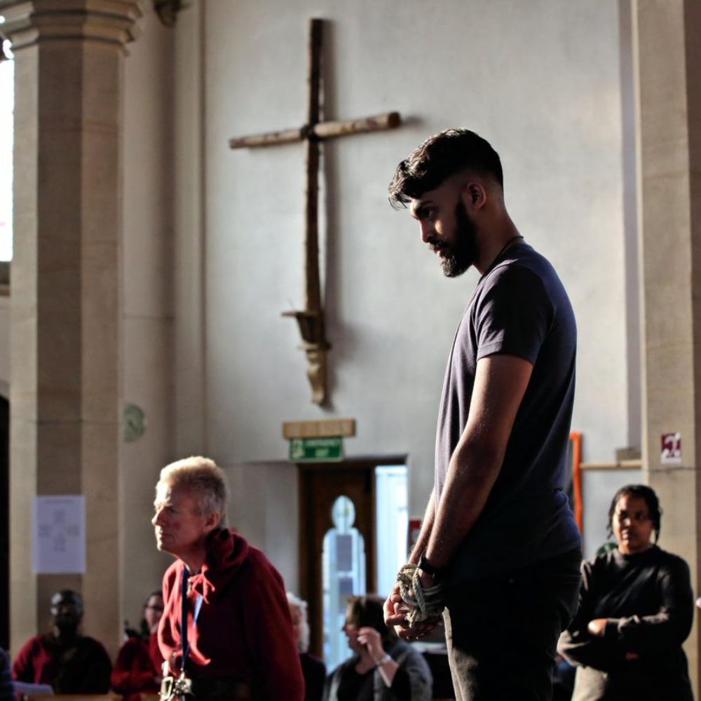 Amateur actors practice the passion play at St Matthew's Church, a large wooden crucifix is on the wall in the background.