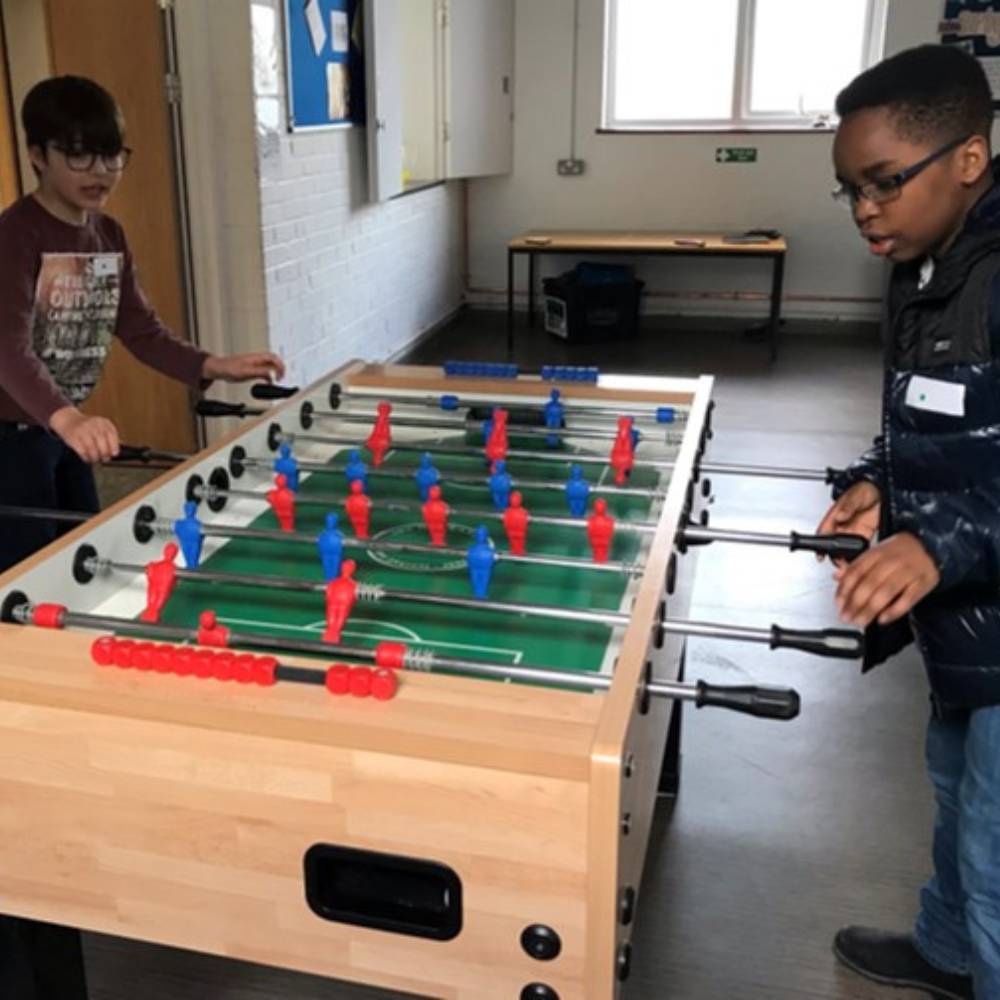 Two young boys playing table football inside.
