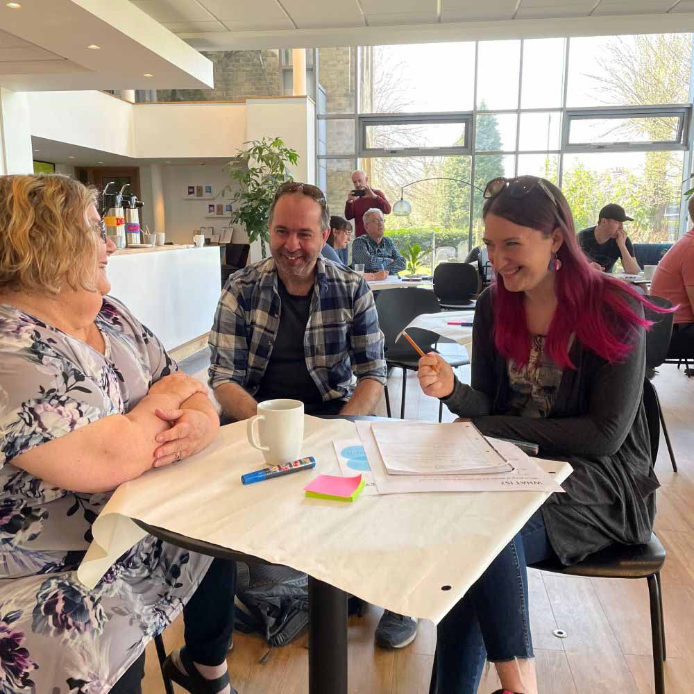 Two women and a man laugh as they chat together