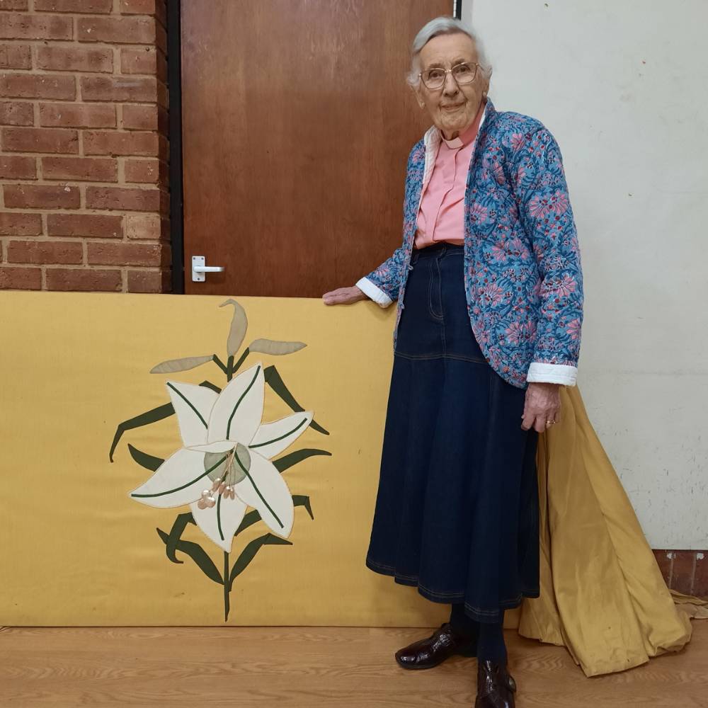 Stella stands next to one of the hand embroidered altar frontals.