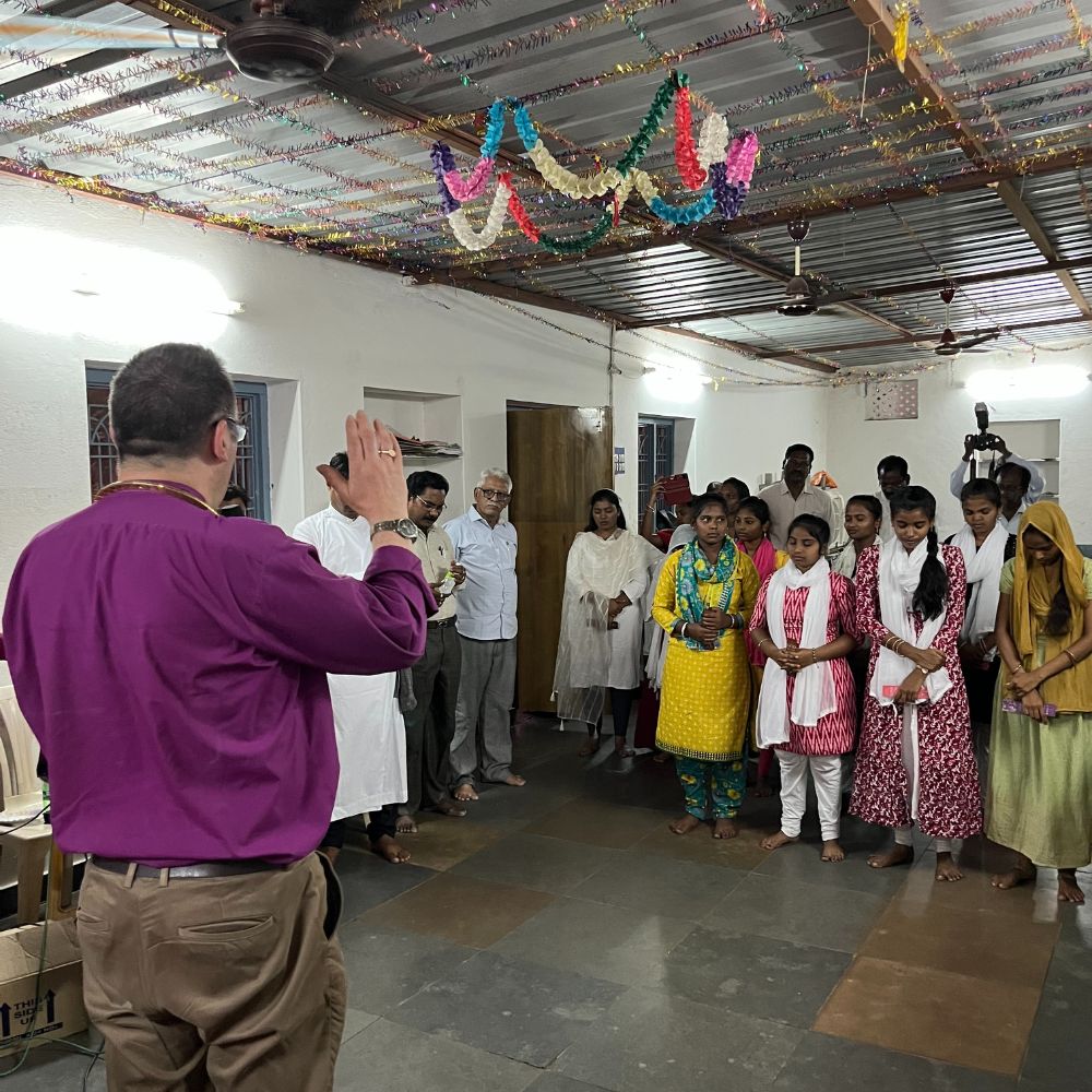 Bishop Gavin stands giving a blessing to members of the Church of South India
