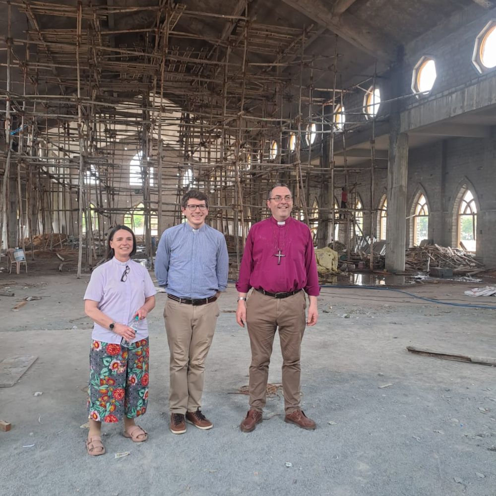 Bishop Gavin, Sarah and James stand in a church building still under construction