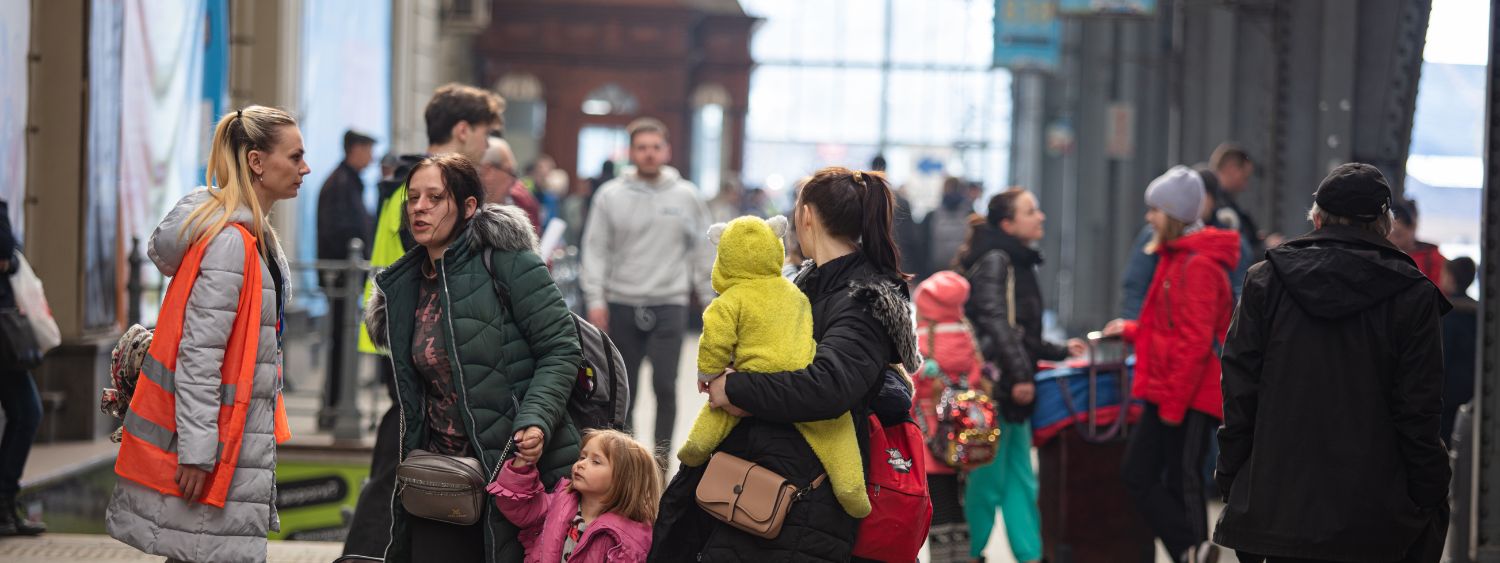 Refugee families seeking help from a volunteer at a European train station.